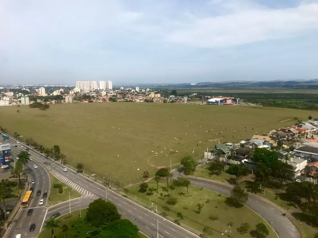 Vista aérea do Terreno das Vaquinhas com gado pastando e os prédios do Jardim Aquarius ao fundo